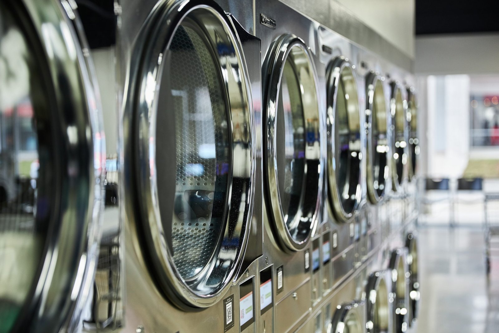 A close-up row of front-load commercial washers in a laundromat