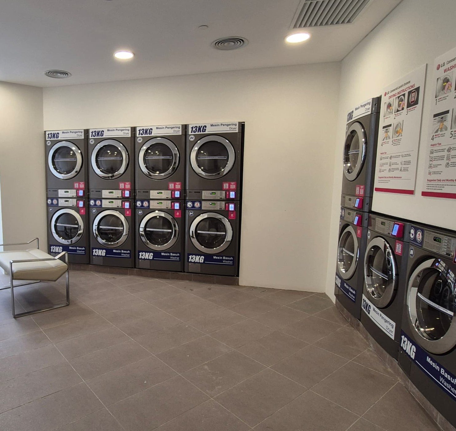Grey-tiled laundromat with stacked washer-dryers along two walls